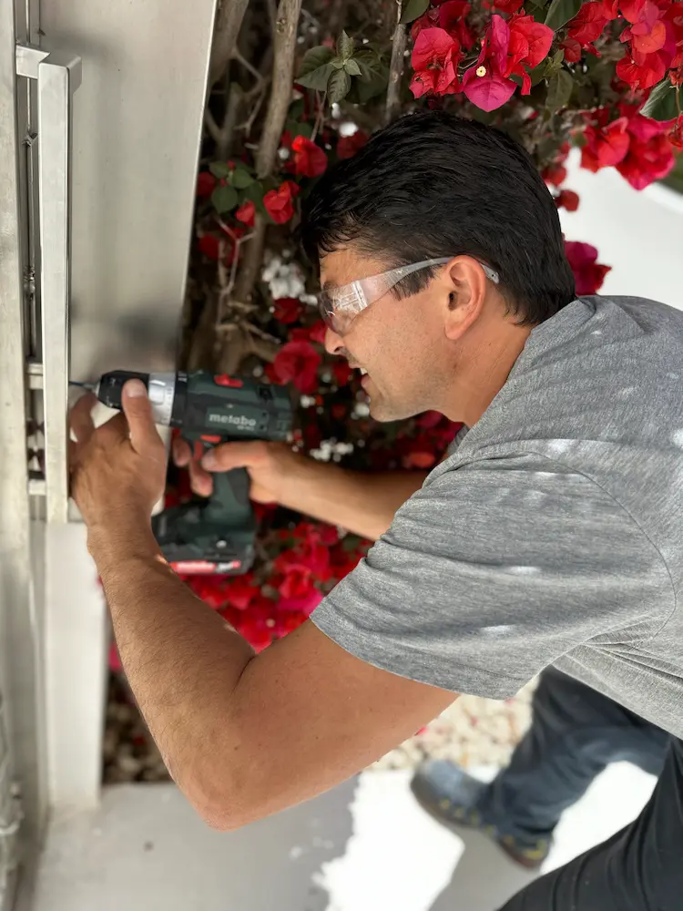 cerrajero urgente en ibiza reparando cerradura de puerta de jardin de comunidad de vecinos en portal de ibiza taladro y gafas protectoras